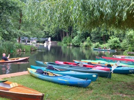 Kanuboote mit Paddeln auf der Wiese am Fließ