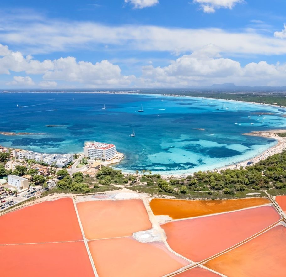 Blick auf eine Küstenlandschaft mit bunten Salzfelder und türkisblauem Wasser.