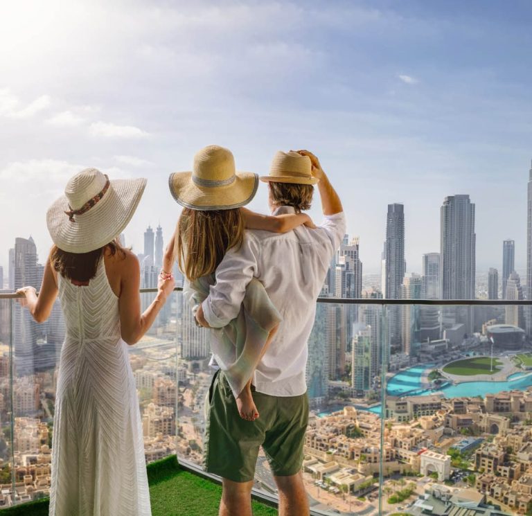 Paar und Frau in Sommerkleidung blicken auf Dubai City