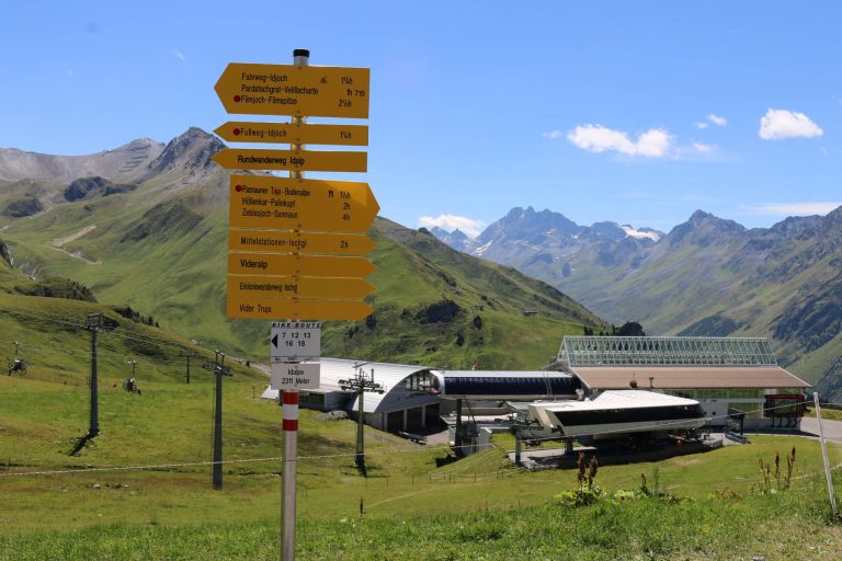 Wegweiser und Bergbahnstation in Ischgl und Galtür