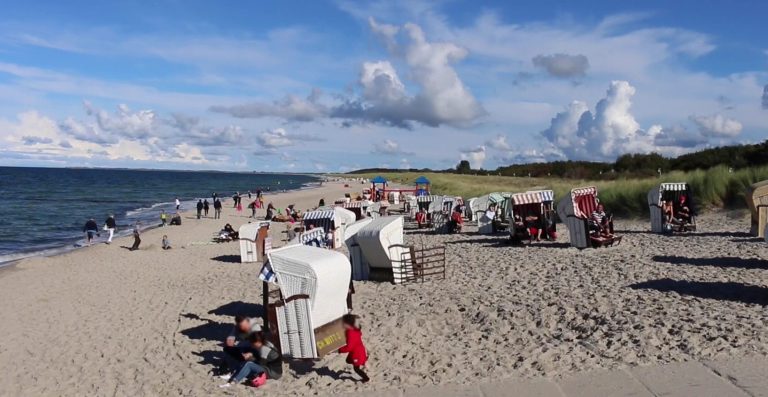 Urlauber am Strand mit weißen Strandkörben