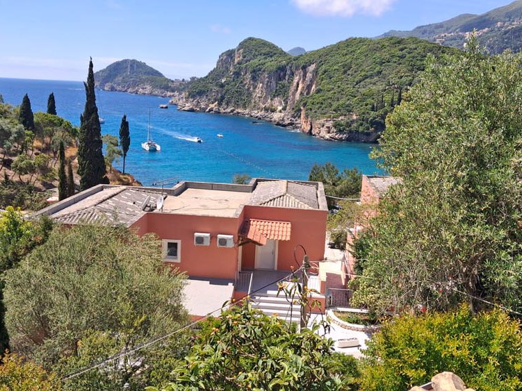 Ausblick vom Balkon in die Bucht von Liapades auf Korfu Häuser mit Blick auf eine Küstenlandschaft und blaues Wasser in einer Bucht.