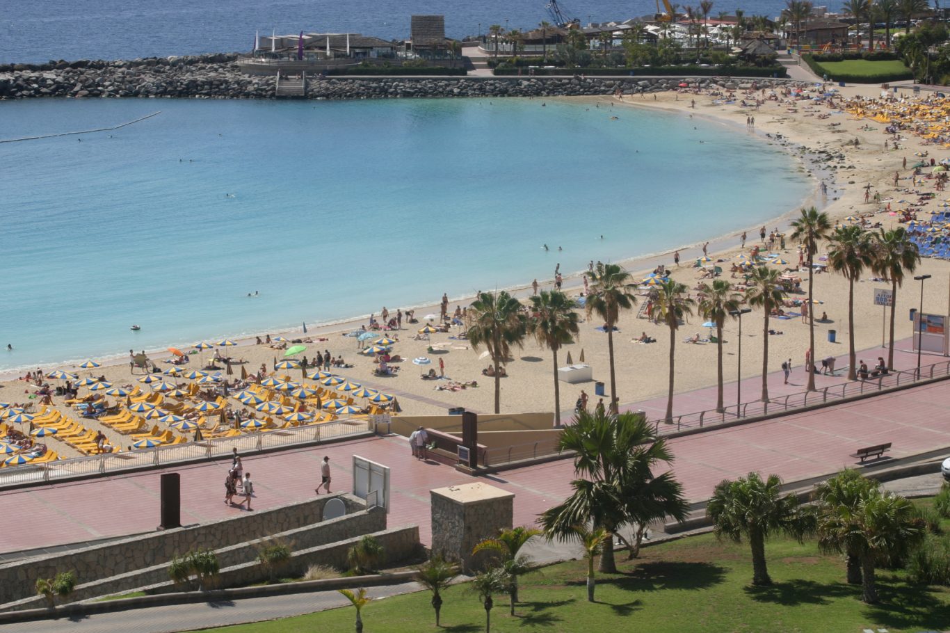 Gran Canaria - weiter Sandstrand an der Playa de Amadores Blick von oben auf den Sandstrand mit blauem Wasser und Palmen an der Playa de Amadores