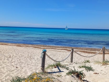 Sandstrand mit blauem Wasser und Segelboot