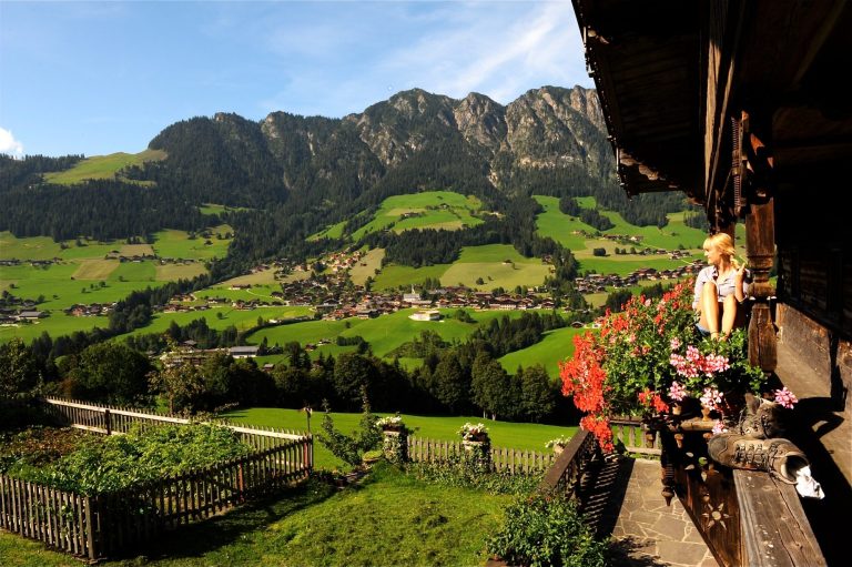 Frau auf Balkonin Alpbach mit Gipfeln im Hintergrund