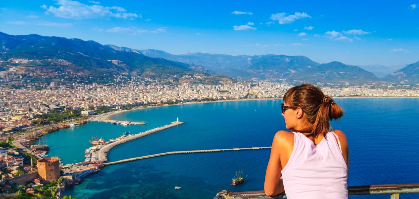 Frau blickt auf Hafen und Küsten von Alanya