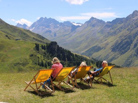 Urlauber in Sonnenliegen vor Gebirgspanorama