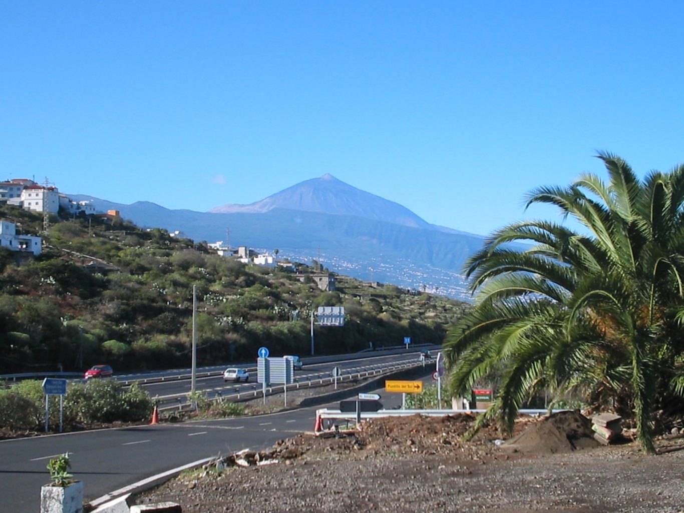 Teneriffa - Blick auf den Teide aus dem Nordosten Vulkan Teide hinter Palmen und einer Autobahn