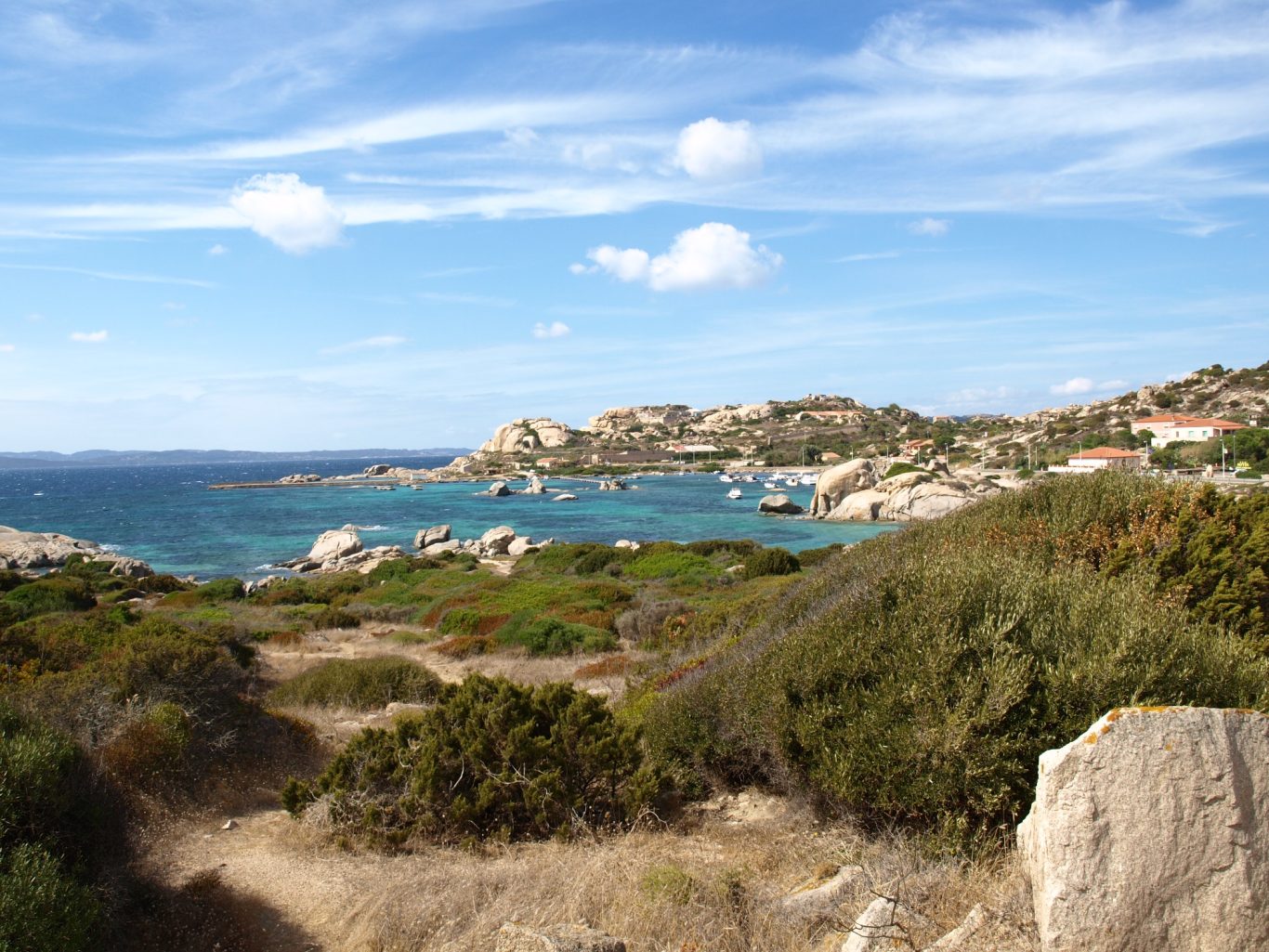 Sardinien - Küstenlandschaft auf La Maddalena Sträucher und Steine mit Felsen und Meer im Hintergrund